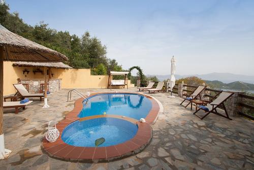 a swimming pool in a patio with chairs and a house at Villa Fotini in Skiathos