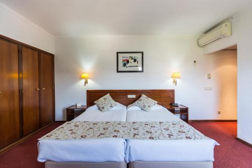 a bedroom with a large bed with two pillows at Hotel Arangues in Setúbal