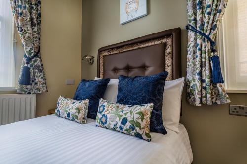 a bedroom with a bed with blue pillows at The Golden Lion Hotel, St Ives, Cambridgeshire - The Coaching Inn Group in St Ives