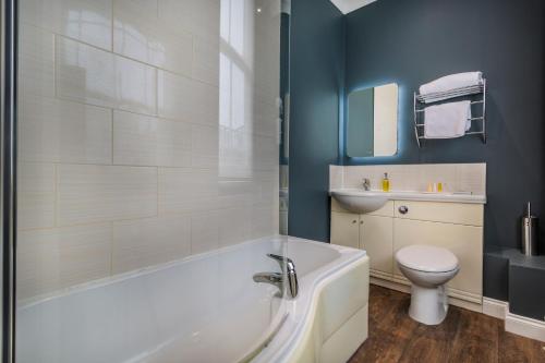 a bathroom with a tub and a toilet and a sink at The Golden Lion Hotel, St Ives, Cambridgeshire - The Coaching Inn Group in St Ives