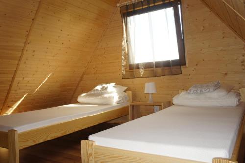 two beds in a wooden cabin with a window at Domki Letniskowe Bryza in Jarosławiec
