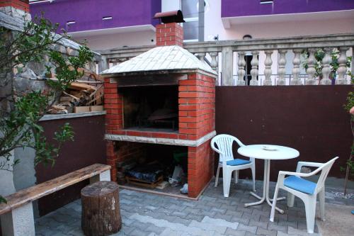 uma lareira de tijolos com 2 cadeiras e uma mesa num pátio em Apartment Antonia em Vodice
