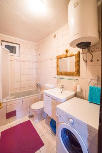 a bathroom with a toilet sink and a washing machine at Apartmani Kala in Podgora