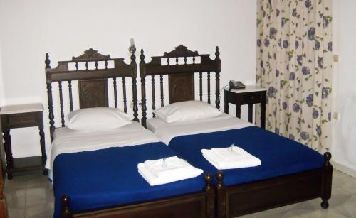 a bedroom with two beds with blue and white sheets at Katsaraki Fotini in Myrina