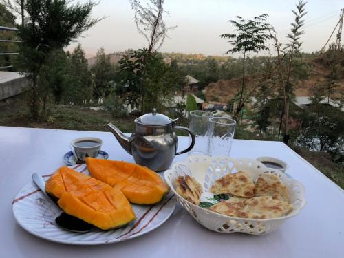 stolik z dwoma talerzami jedzenia i dzbanek do herbaty w obiekcie Mini Lalibela Guest House w mieście Lalibela