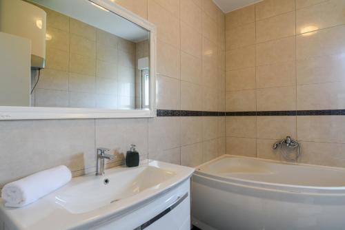 een badkamer met een wastafel, een bad en een spiegel bij Villa Apartment AA 2 in Trogir