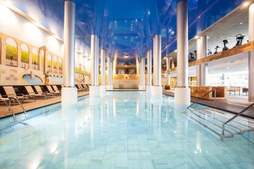 a large pool in a building with white columns at Grupotel Playa de Palma Suites & Spa in Playa de Palma