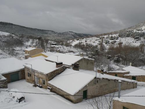 a village covered in snow with mountains in the background at Ciudad Encantada Tio Daniel in Valdecabras