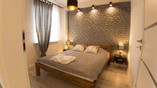 sypialnia z ceglaną ścianą i łóżkiem z 2 poduszkami w obiekcie Apartament Termalny Komfort 8.1 w Uniejowie