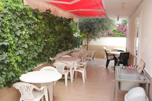 a patio with tables and chairs and a green wall at Ozge Pansiyon in Didim