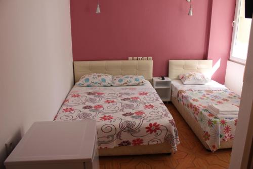 a small bedroom with two beds and pink walls at Ozge Pansiyon in Didim