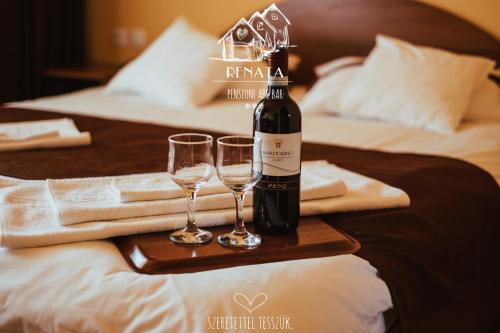 una botella de vino y dos copas de vino en una mesa en Pensiunea Renata, en Boghiş