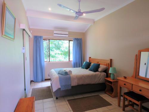 a bedroom with a bed with blue curtains and a window at 102 Siyayi in Mtunzini