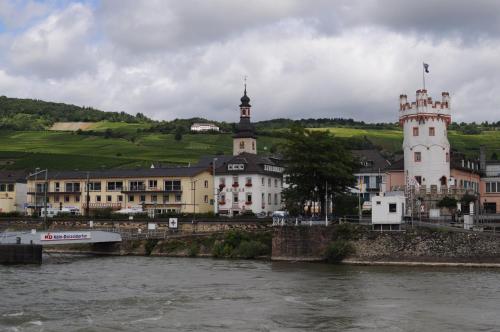 a town next to a river with a bridge and buildings at Hotel Krone Rüdesheim in Rüdesheim am Rhein