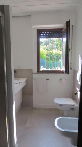 a white bathroom with a window and a toilet at B&B Casa Soresina in Offagna