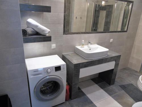ein Badezimmer mit einer Waschmaschine und einem Waschbecken in der Unterkunft MOne - fajny apartament w centrum Wrocławia in Breslau