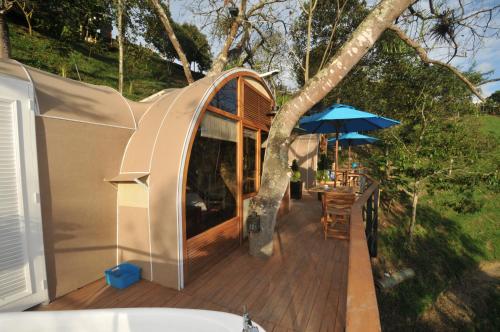 a house with a deck with an umbrella and a table at Hotel Casa Ambrosia in Villeta