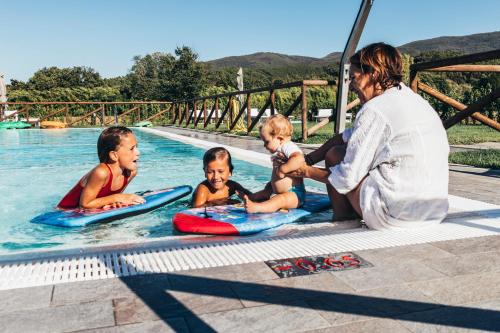 a woman sitting next to three children in a swimming pool at Tenuta San Giovanni Lucca in Lucca