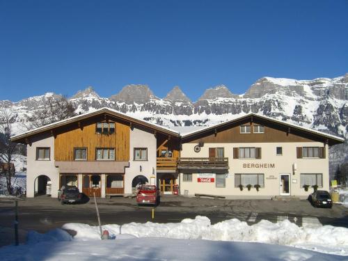 a large building with snow covered mountains in the background at Hotel Restaurant Bergheim in Flumserberg