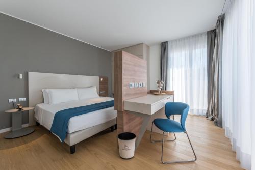 a hotel room with a bed and a chair at Hesperia Hotel & Residence in Lido di Jesolo