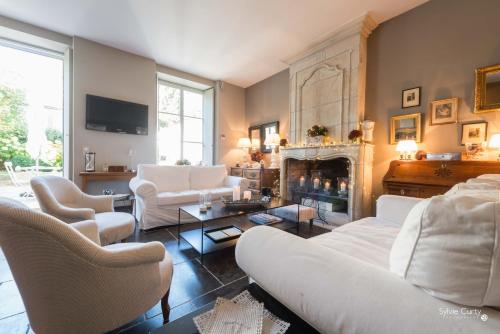a living room with white furniture and a fireplace at Entre Hotes in La Rochelle