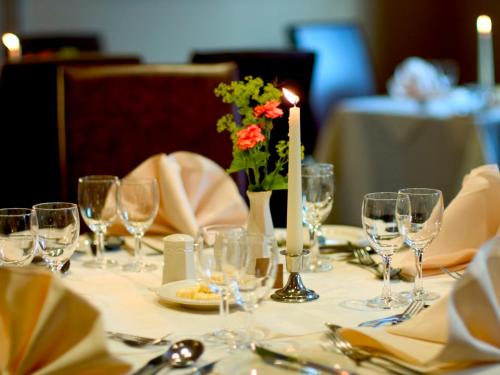 a table with glasses and a candle and a vase with flowers at Metropole Hotel and Spa in Llandrindod Wells
