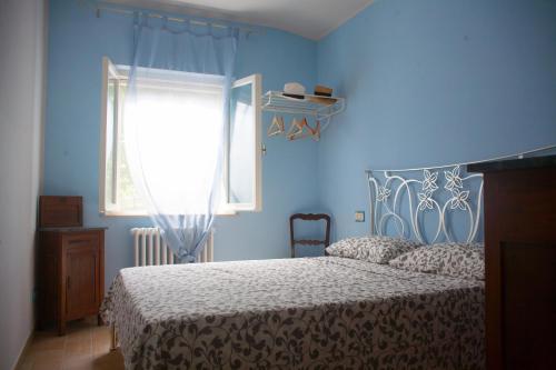 a blue bedroom with a bed and a window at Casa vacanze a Rubbianello in Monterubbiano