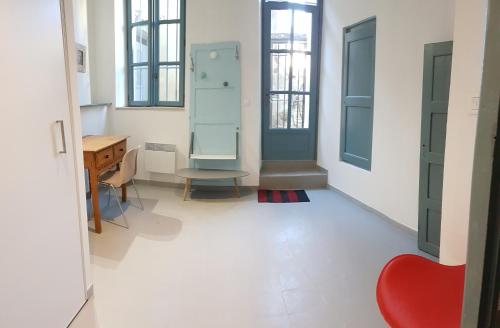 Cette chambre dispose d'une chaise rouge, d'un bureau et de fenêtres. dans l'établissement L'Escalier Rouge, à Arles