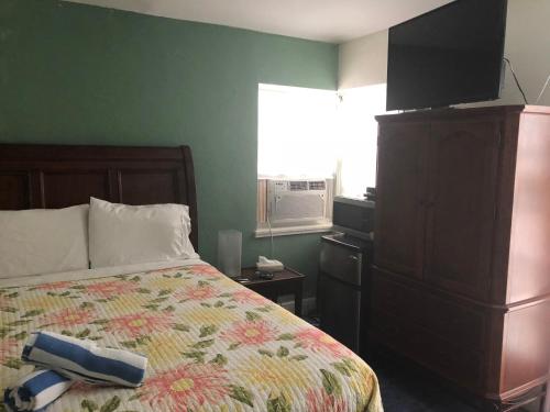 a bedroom with a bed with a dresser and a television at Calypso Inn Wilton Gay Male Resort in Fort Lauderdale