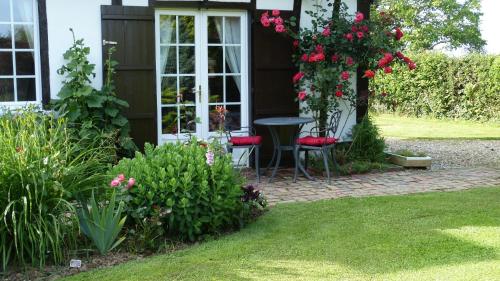 a house with a table and flowers in the yard at Le Petit Verger in Grumesnil