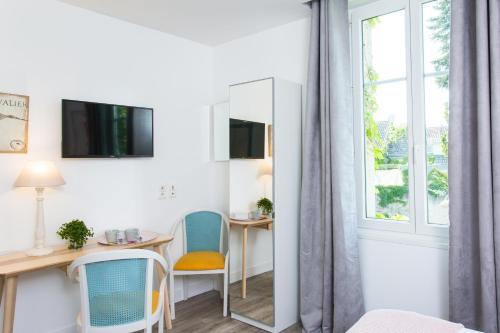 een kamer met een bureau, stoelen en een spiegel bij Logis Hôtels Restaurant La Mère Hamard in Semblançay