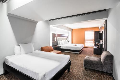 a hotel room with two beds and a chair at Exe Cities Reforma in Mexico City