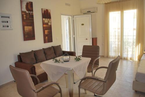 a living room with a couch and a table and chairs at Laskas Apartment in Stalida