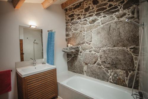 baño con pared de piedra, bañera y lavamanos en O Curralino, en Vilacoba