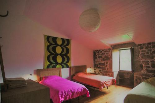 a room with two beds and a stone wall at O Curralino in Vilacoba
