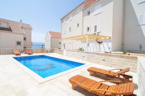 a swimming pool with two deck chairs and a pool at Apartments Sara 3 in Bol