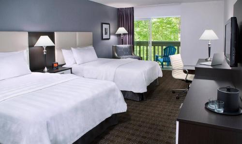 a hotel room with two beds and a desk at Toronto Don Valley Hotel and Suites in Toronto