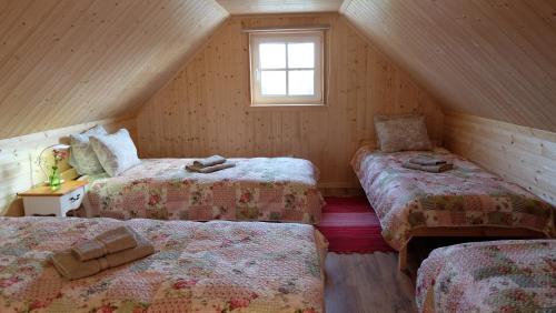 a attic room with three beds and a window at Tahula Puhkemaja in Tahula