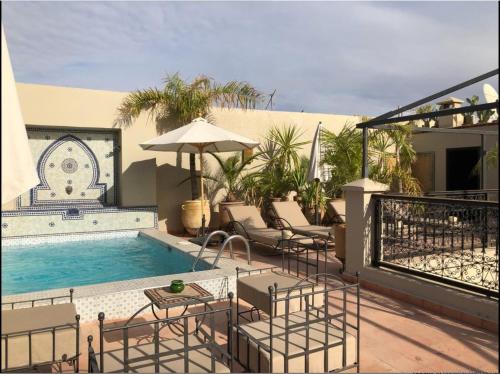 une terrasse avec une piscine, des chaises et un parasol dans l'établissement Riad le Clos des Arts, à Marrakech