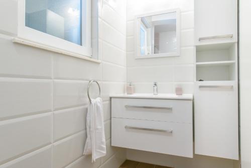 a white bathroom with a sink and a mirror at Villa Lucia, peacefull and private in Mravince