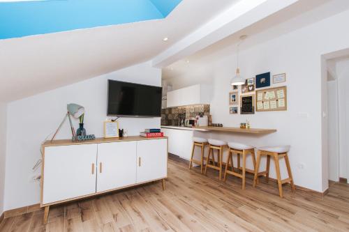 a kitchen with white cabinets and a bar with stools at Fyaka Loft Apartments in Vodice
