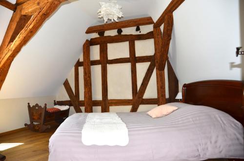 Un dormitorio con una gran cama de madera con sábanas blancas. en La Parenthèse en Kaysersberg