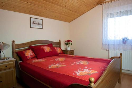a bedroom with a bed with red sheets and a window at M&aacute;ria-lak Zalakaros in Zalakaros