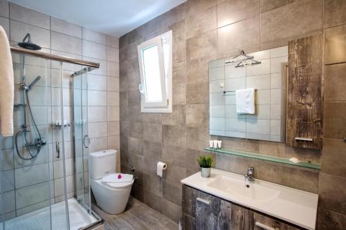 a bathroom with a toilet and a sink and a shower at Isalos Suites in Néa Péramos