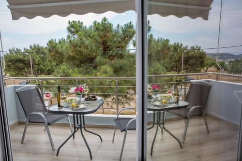 a table and chairs on a balcony with a view at Isalos Suites in Néa Péramos