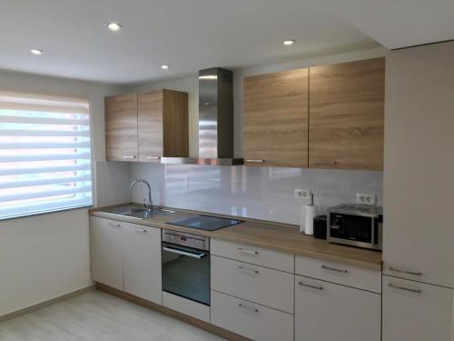 a kitchen with white cabinets and a sink and a microwave at Apartma Sonja in Piran