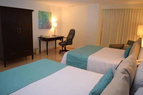 a hotel room with two beds and a desk at Astur Hotel & Residence in Veracruz