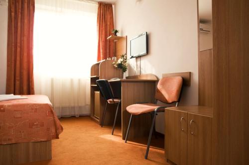 a room with a desk and chairs and a bed at Hotel Est in Bucharest