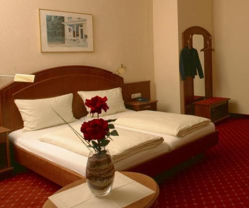 1 dormitorio con 1 cama con un jarrón con flores sobre una mesa en Hotel Schweizer Hof - Superior, en Baden-Baden