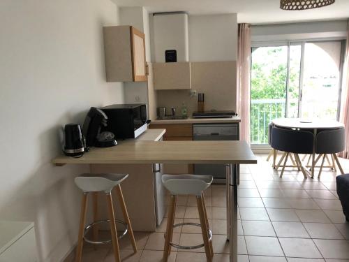 une cuisine avec une table et des tabourets dans une pièce dans l'établissement Studio Cosy à Carnon-Plage, à Carnon-Plage